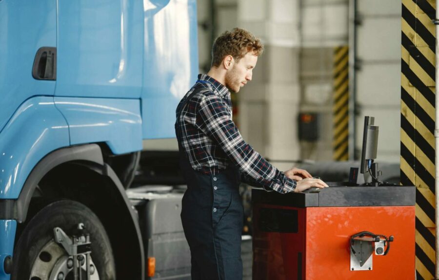 Autobody-shop-employee-working-on-calibarations-on-truck-1200×766 technician working with scan tool on semi truck